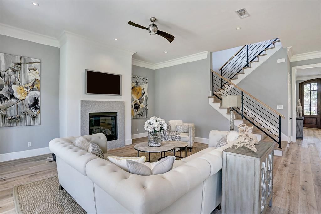 A living room with a couch , fireplace , television and stairs.