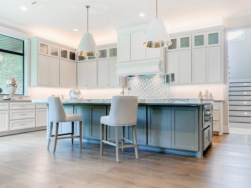 A kitchen with white cabinets and a large island in the middle.
