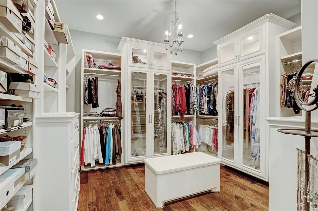 A large walk in closet filled with lots of clothes and a table.