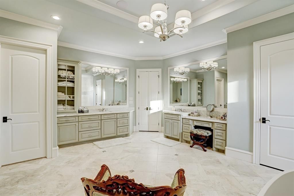 A large bathroom with two sinks , two mirrors , a tub and a chandelier.
