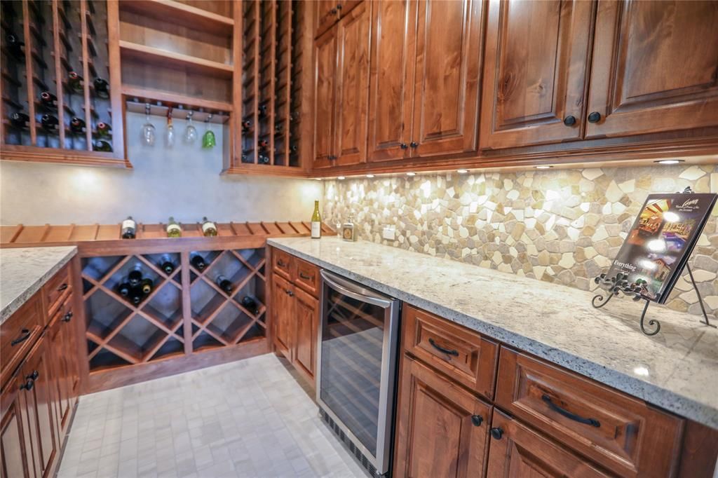 A kitchen with wooden cabinets , granite counter tops , and a wine cooler.