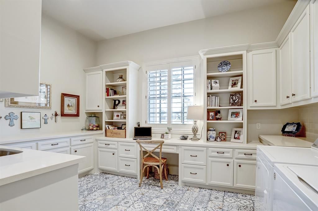 A laundry room with white cabinets , a desk , and a washer and dryer.