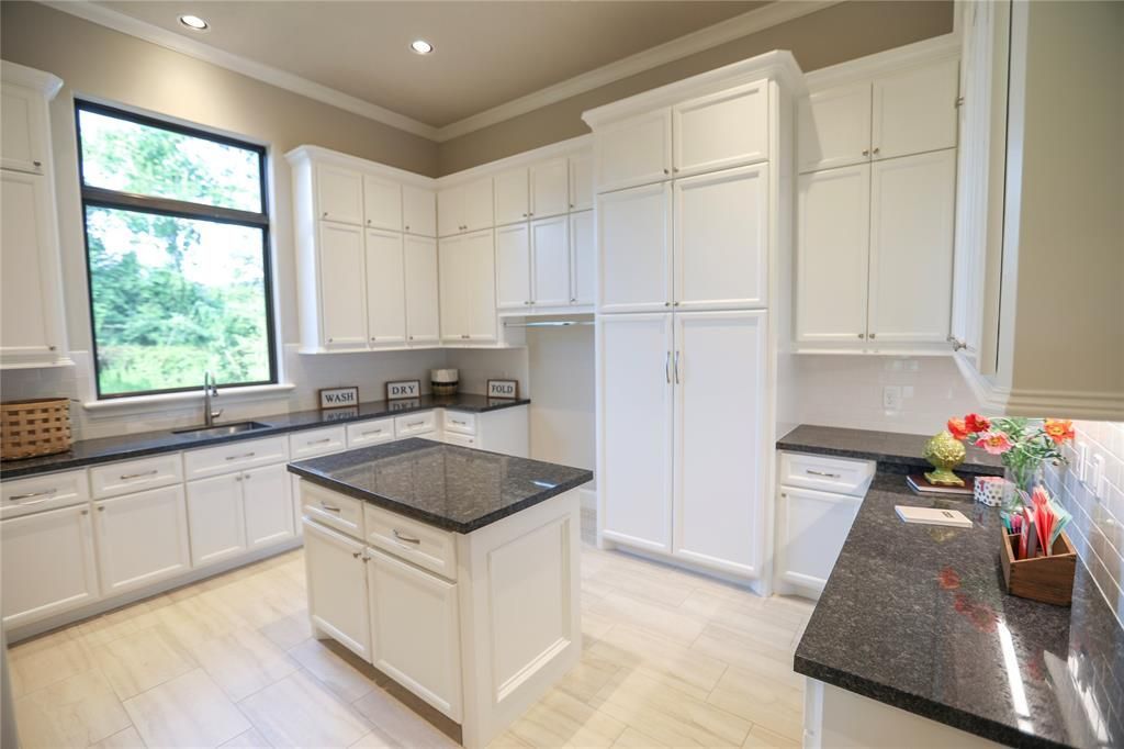 A large kitchen with white cabinets and black granite counter tops.