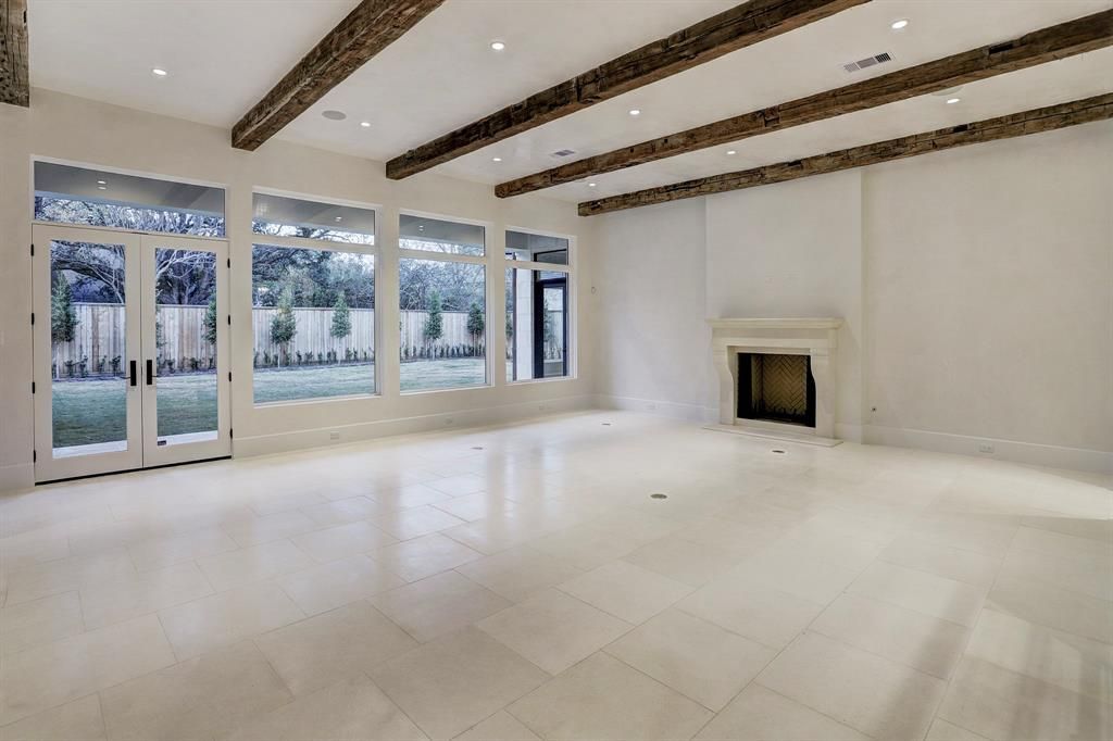 An empty living room with a fireplace and lots of windows.