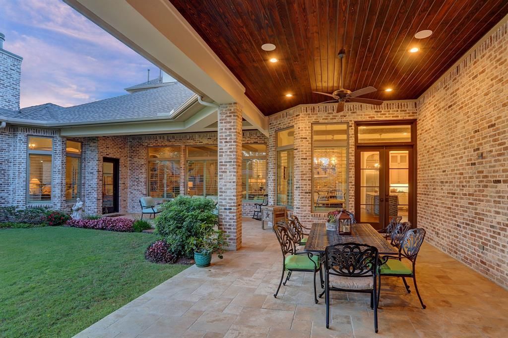 A patio with a table and chairs under a wooden ceiling.