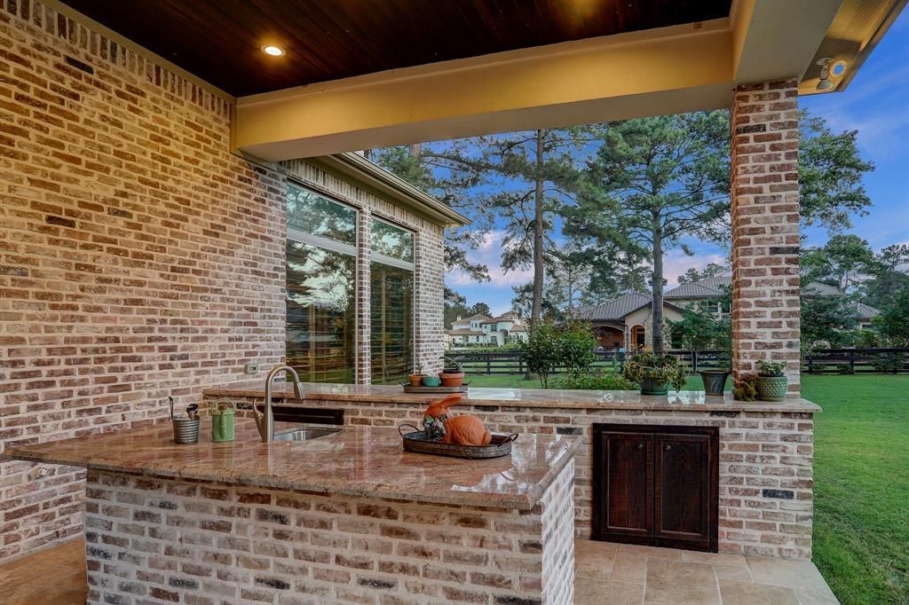 A brick outdoor kitchen with a granite counter top and a sink.