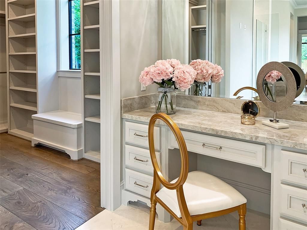 A vanity with a chair and a mirror in a walk in closet.
