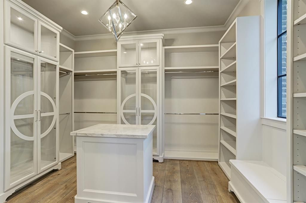 A walk in closet with lots of shelves and a large island in the middle.