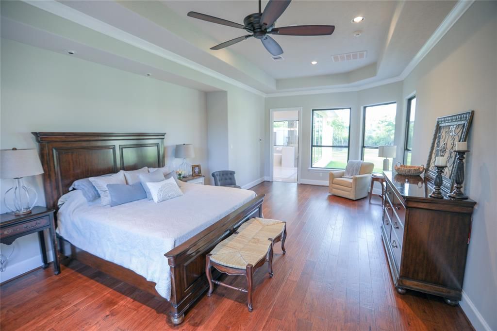 A bedroom with a bed , dresser , chair and ceiling fan.