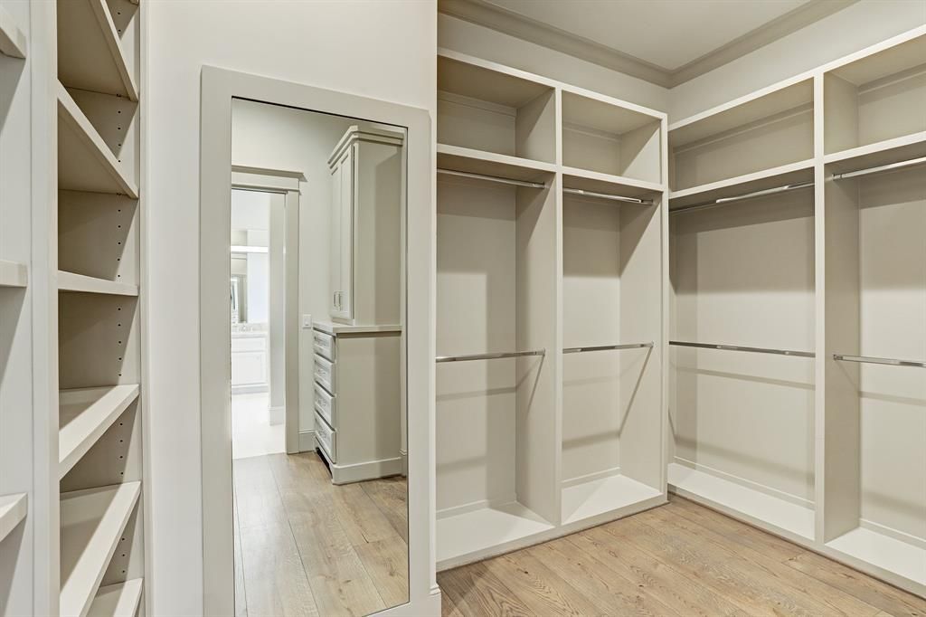 A walk in closet with lots of shelves and a mirror.