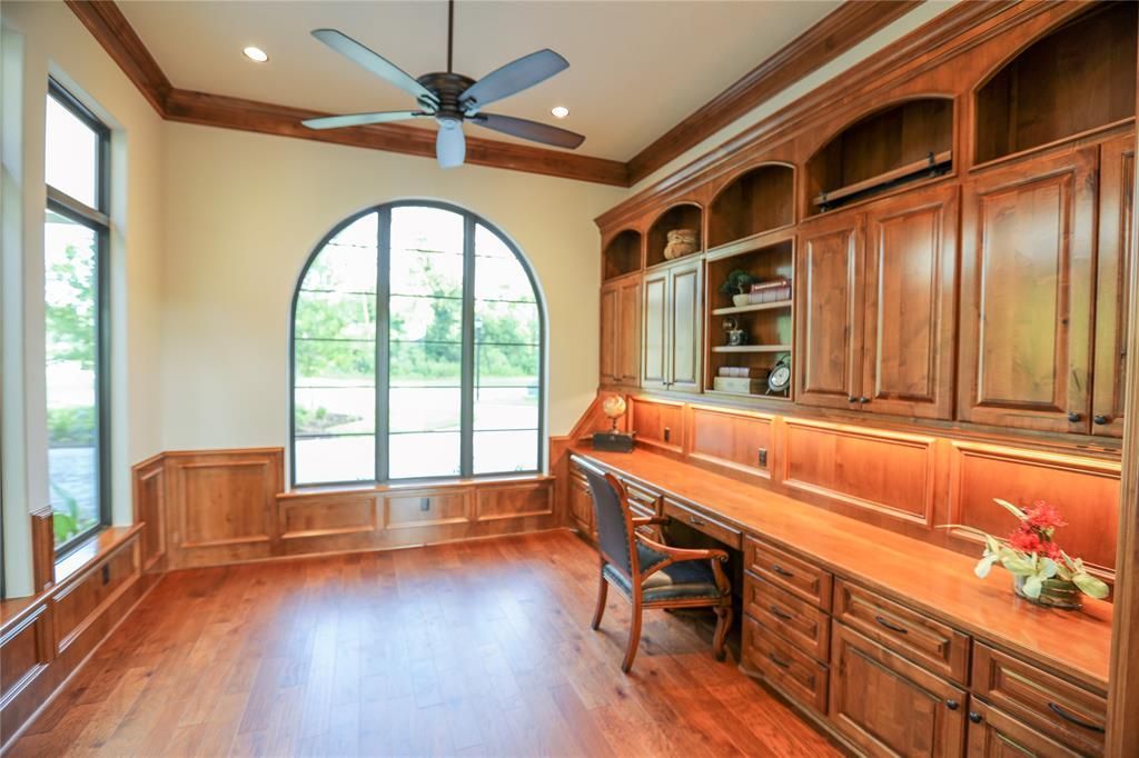 There is a ceiling fan in the room with a desk and chair.
