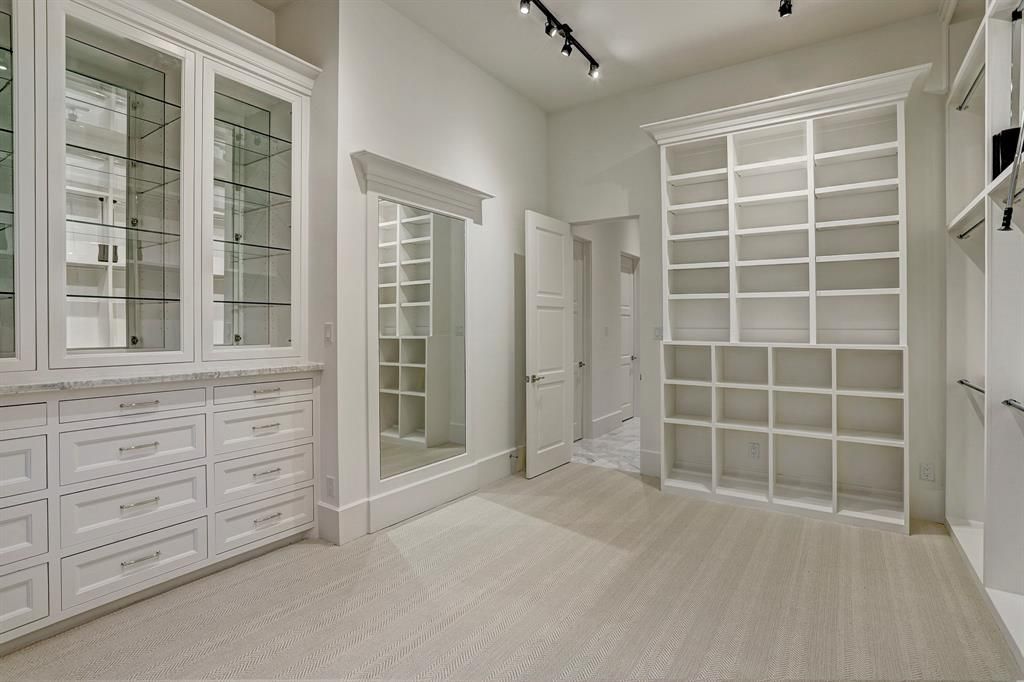 A large walk in closet with lots of shelves and mirrors.