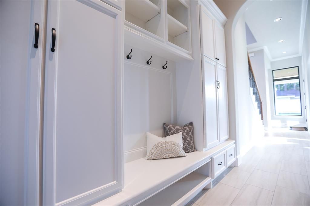 A hallway with white cabinets and a bench with a pillow on it.