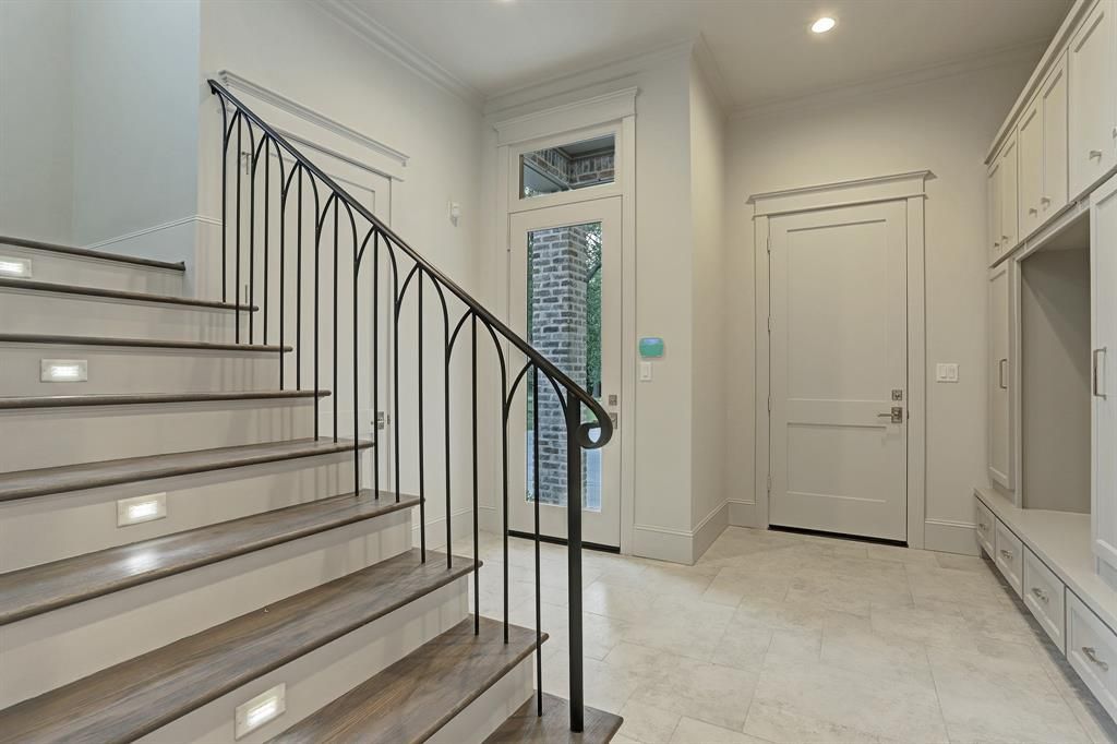 A staircase leading up to the second floor of a house with a wrought iron railing.