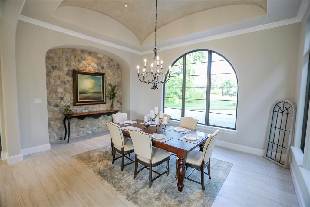 A dining room with a table and chairs and a chandelier hanging from the ceiling.