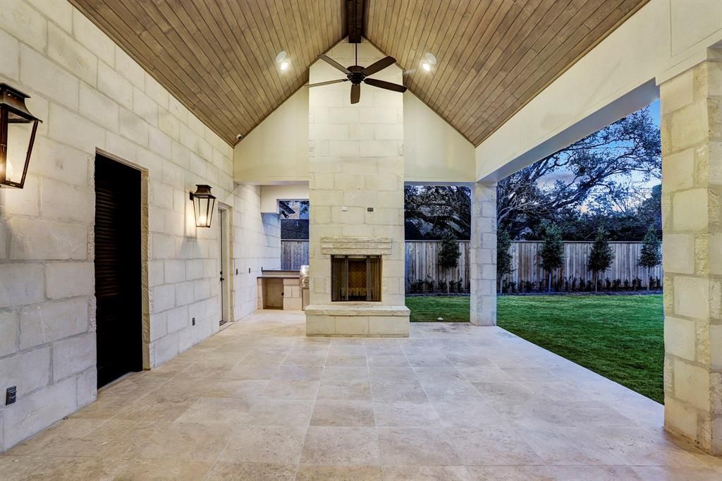 An empty patio with a fireplace and a ceiling fan