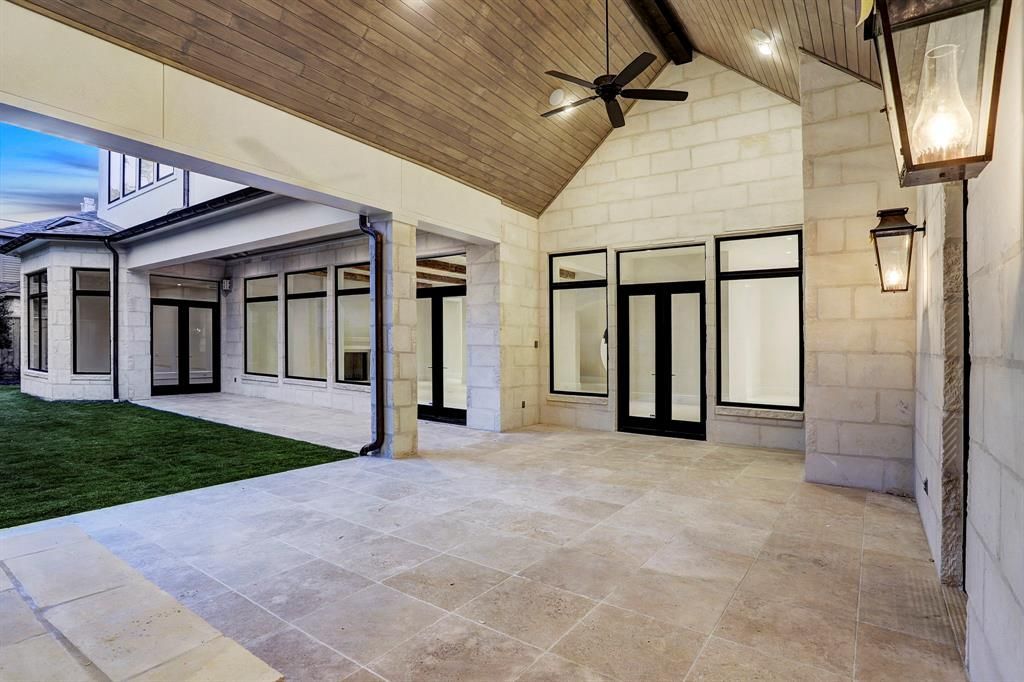 A large patio with a ceiling fan and a lot of windows.