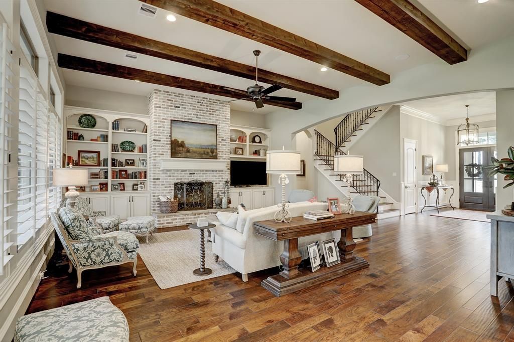 A living room with hardwood floors , a couch , chairs and a fireplace.
