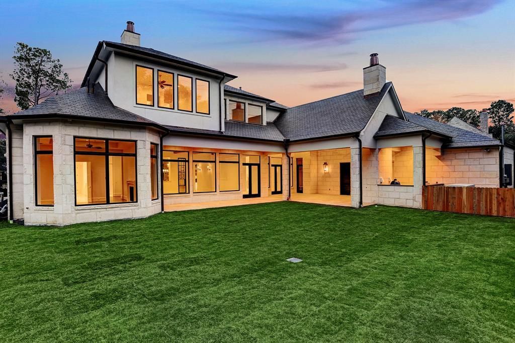 A large white house with a lot of windows is sitting on top of a lush green lawn.