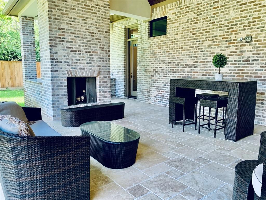 A patio with a fireplace , couch , table and chairs.