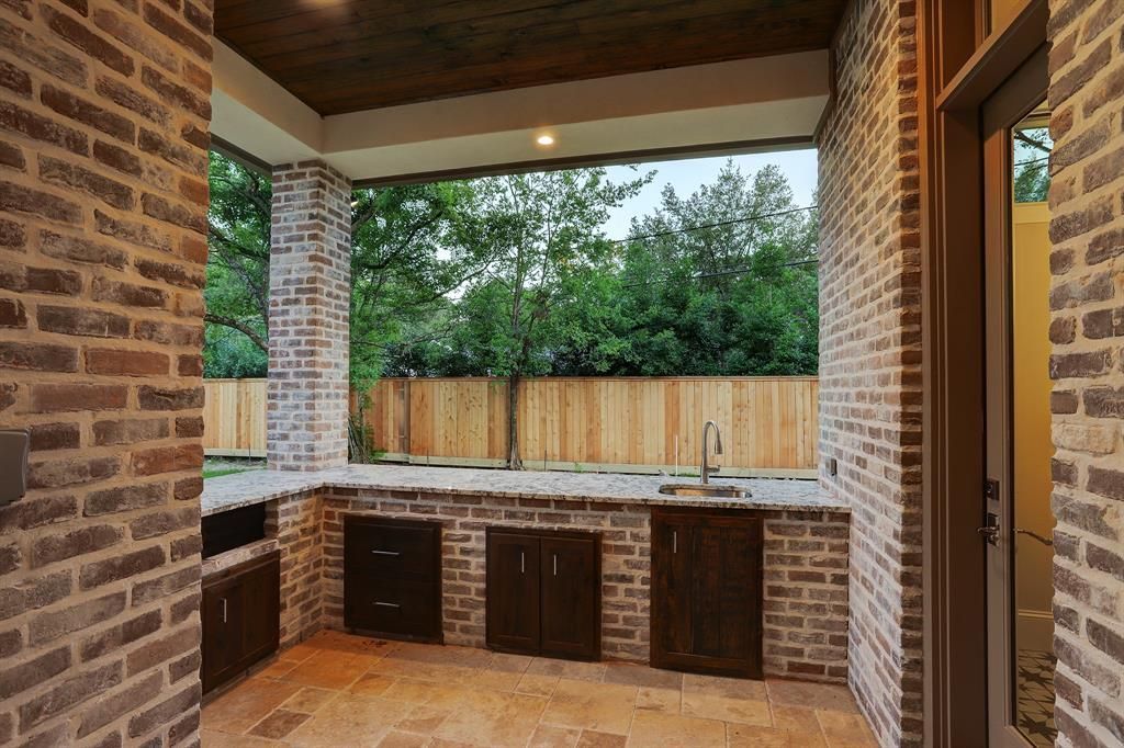 A kitchen with a brick wall and a wooden fence in the background