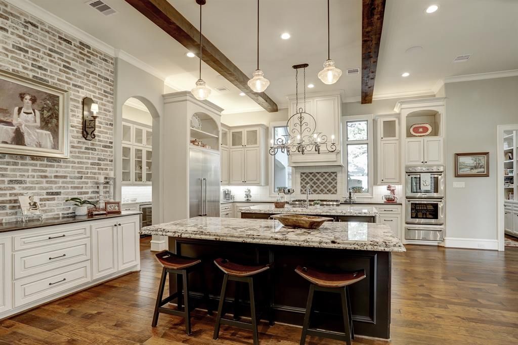 A kitchen with a large island and stools in it.