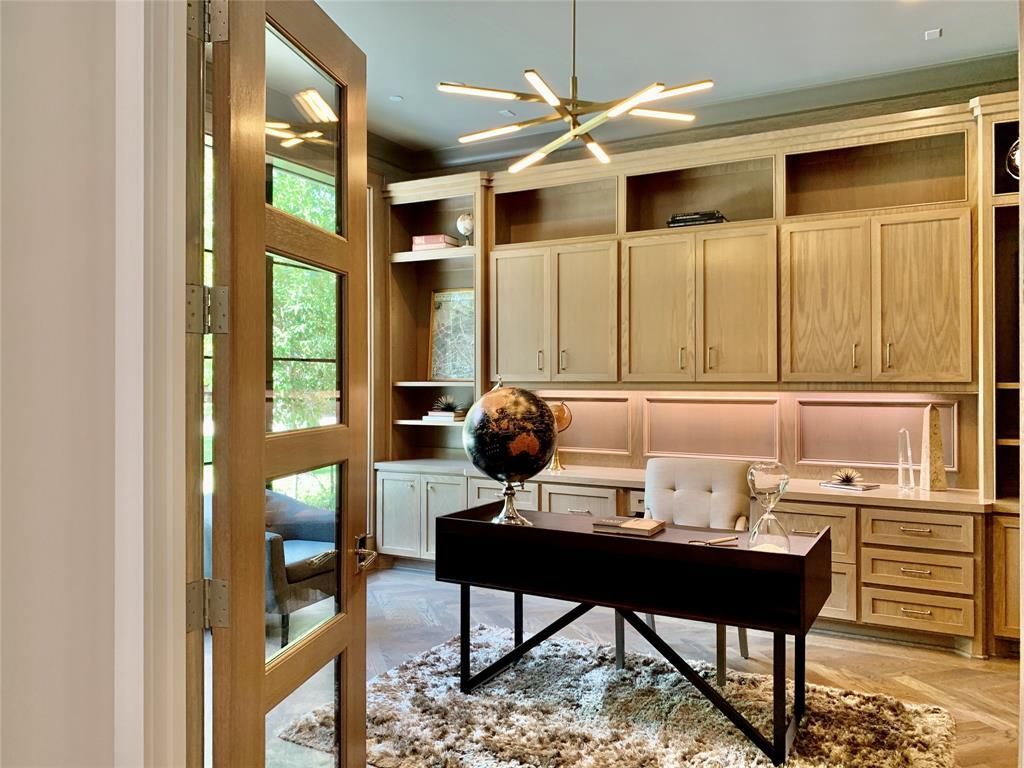 A home office with a desk , chairs , cabinets and a globe on the desk.
