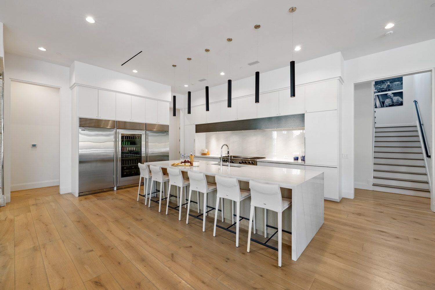 A large kitchen with white cabinets and stainless steel appliances and a large island.
