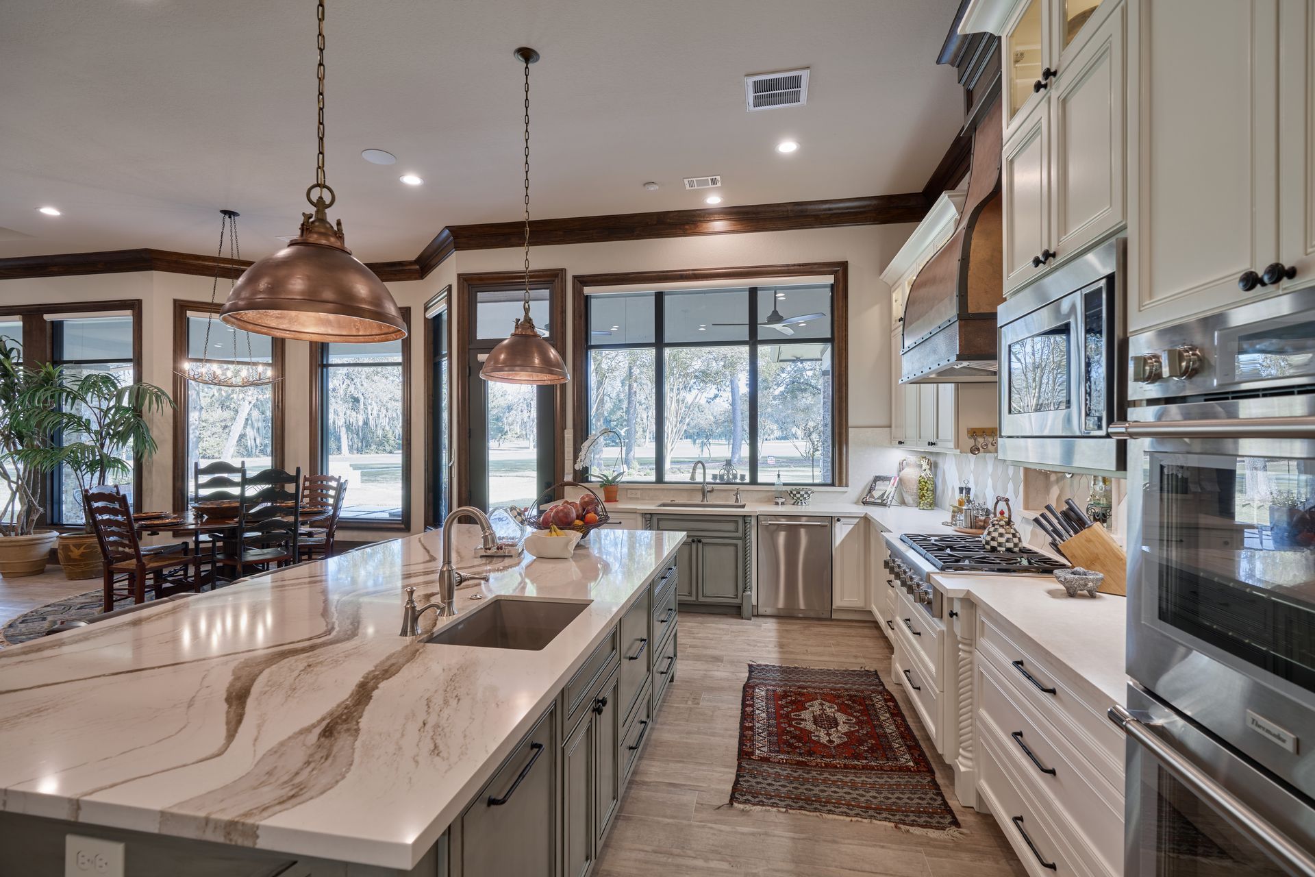 A kitchen with white cabinets , granite counter tops , stainless steel appliances and a large island.