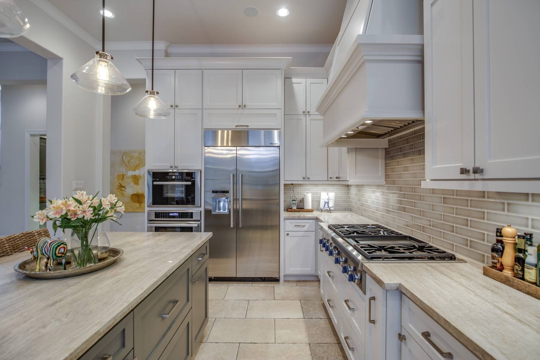 A kitchen with white cabinets , stainless steel appliances and a large island.