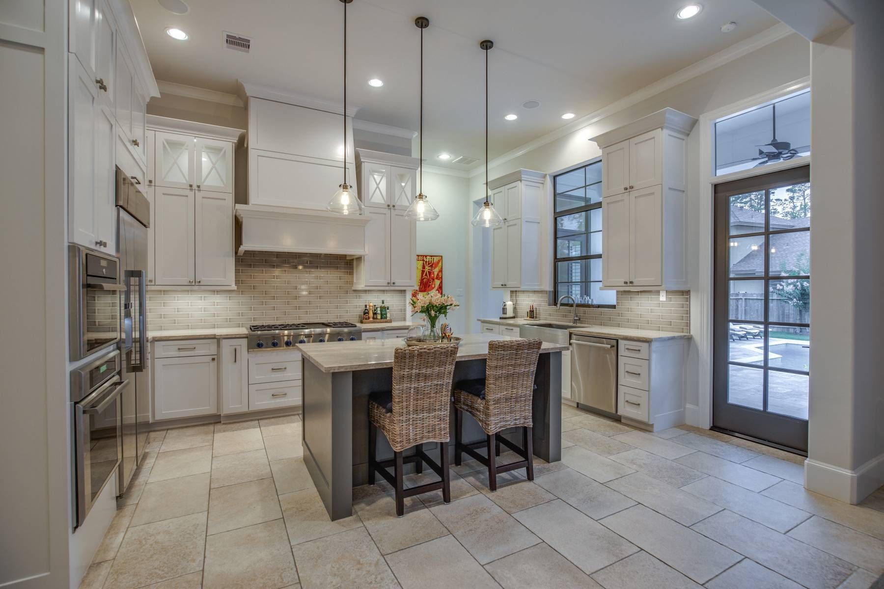 A kitchen with white cabinets , stainless steel appliances , and a large island.