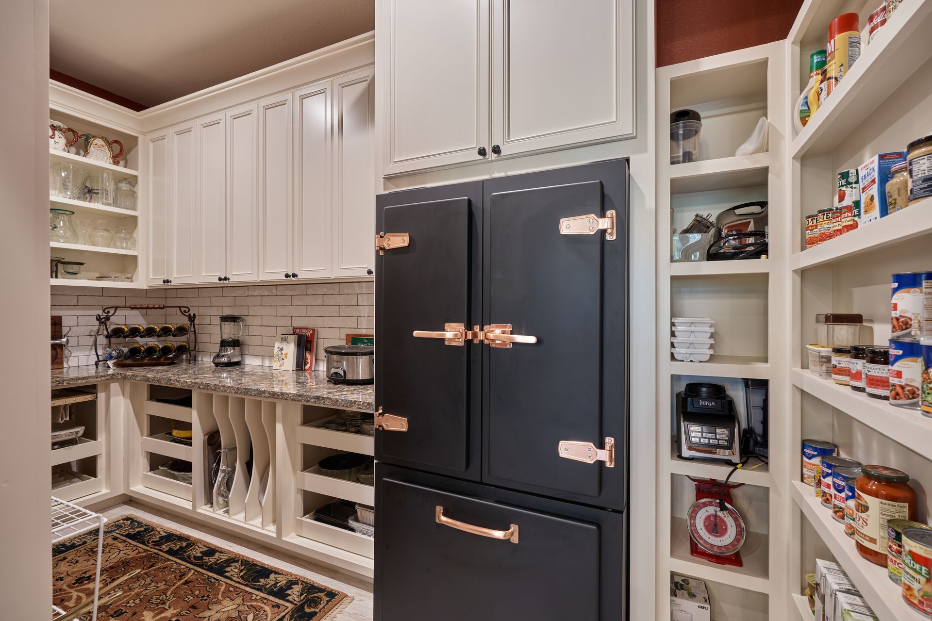 A kitchen with white cabinets and a black refrigerator.