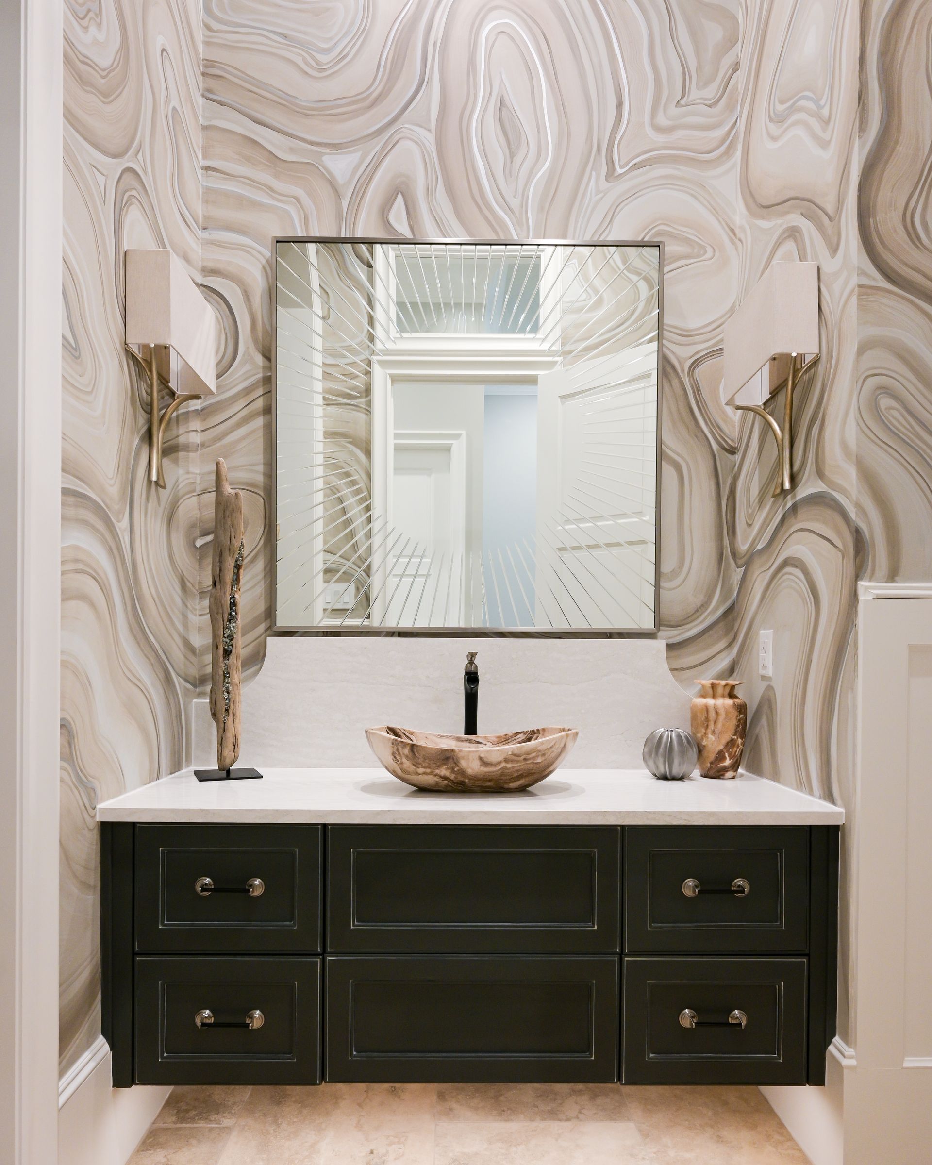 A bathroom with a sink , mirror and marble wallpaper.