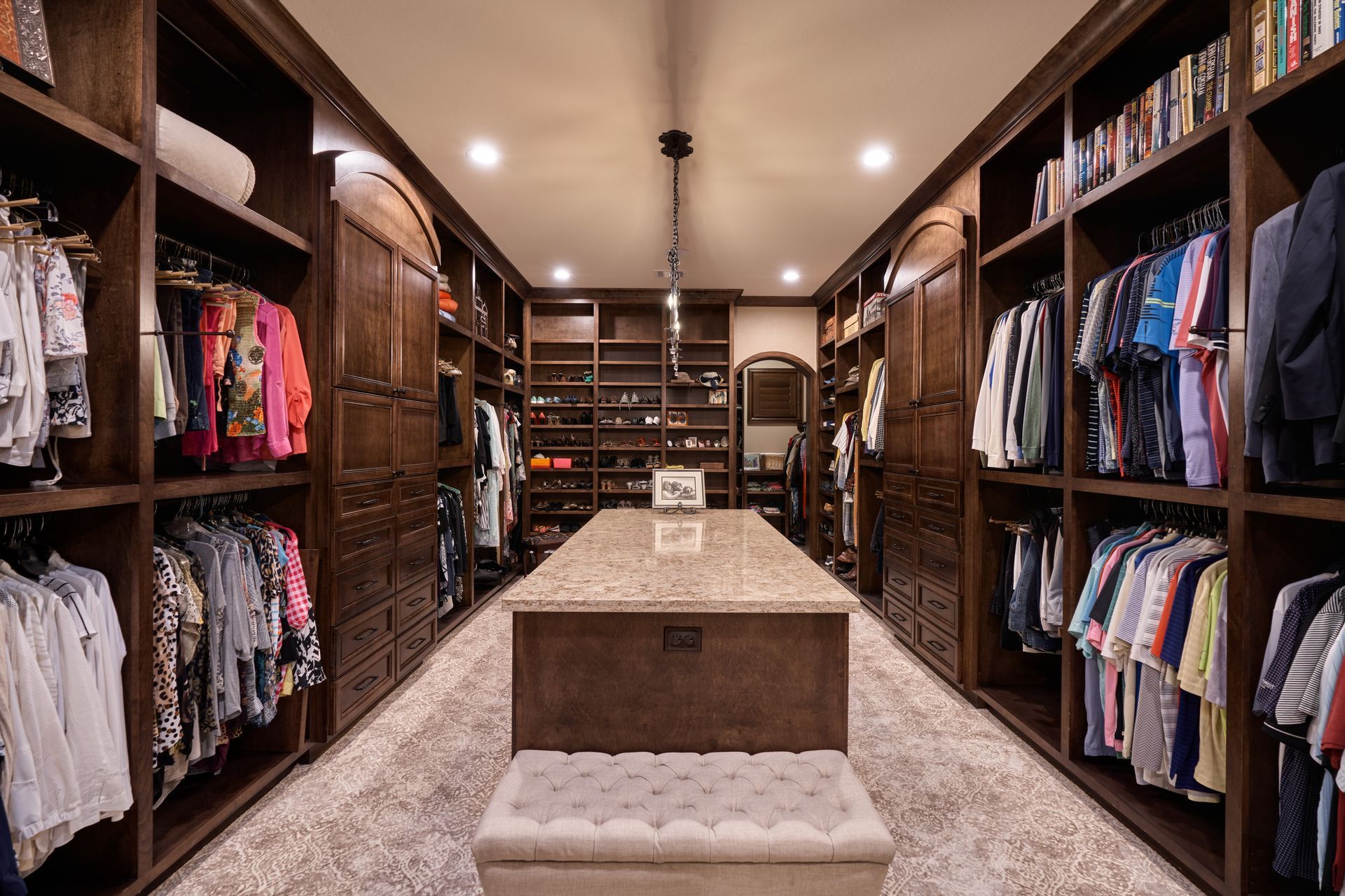 A large walk in closet filled with lots of clothes and a table.