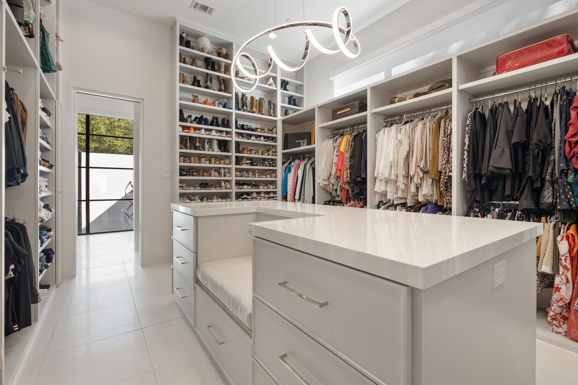 A large walk in closet filled with lots of clothes and shoes.