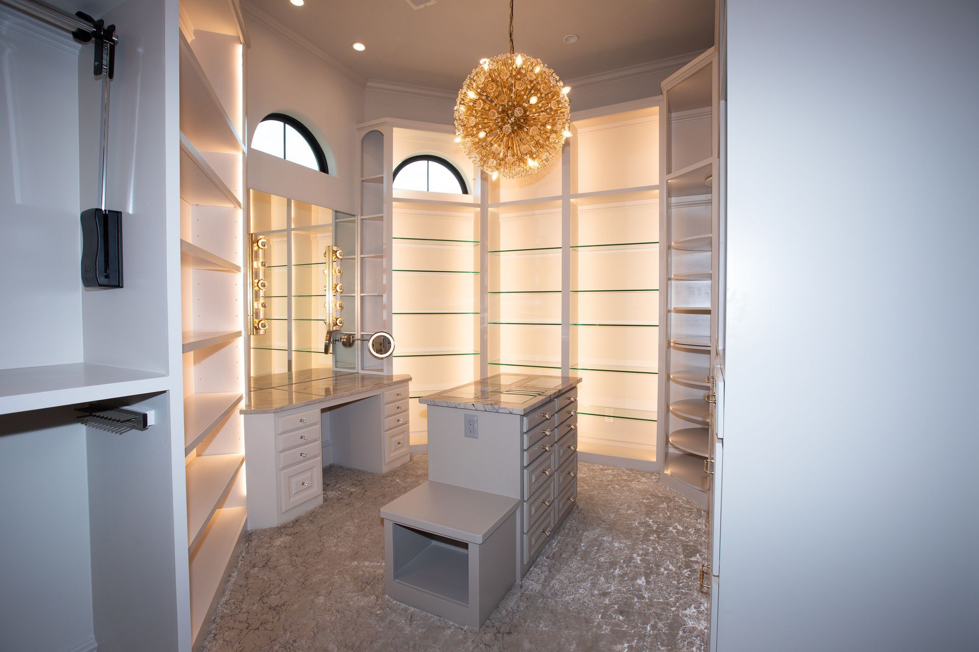 A walk in closet with lots of shelves and a chandelier hanging from the ceiling.