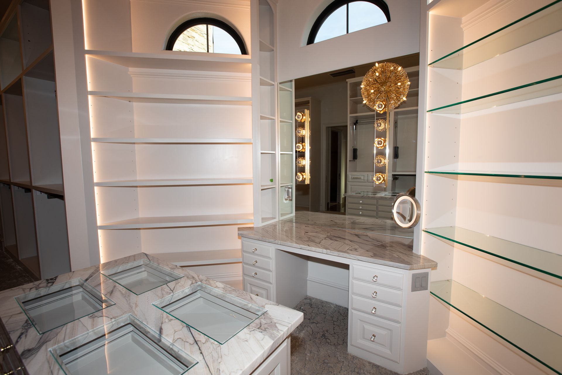 A walk in closet with a vanity , mirror and shelves.