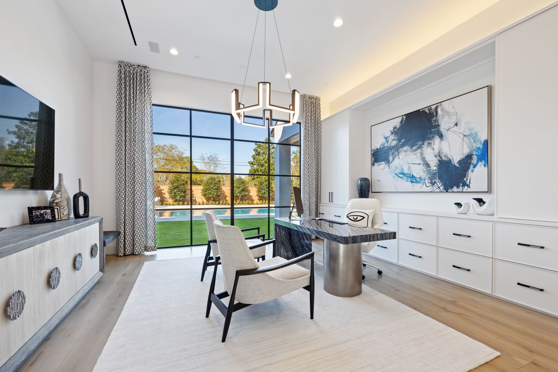A home office with a desk and chairs and a large window
