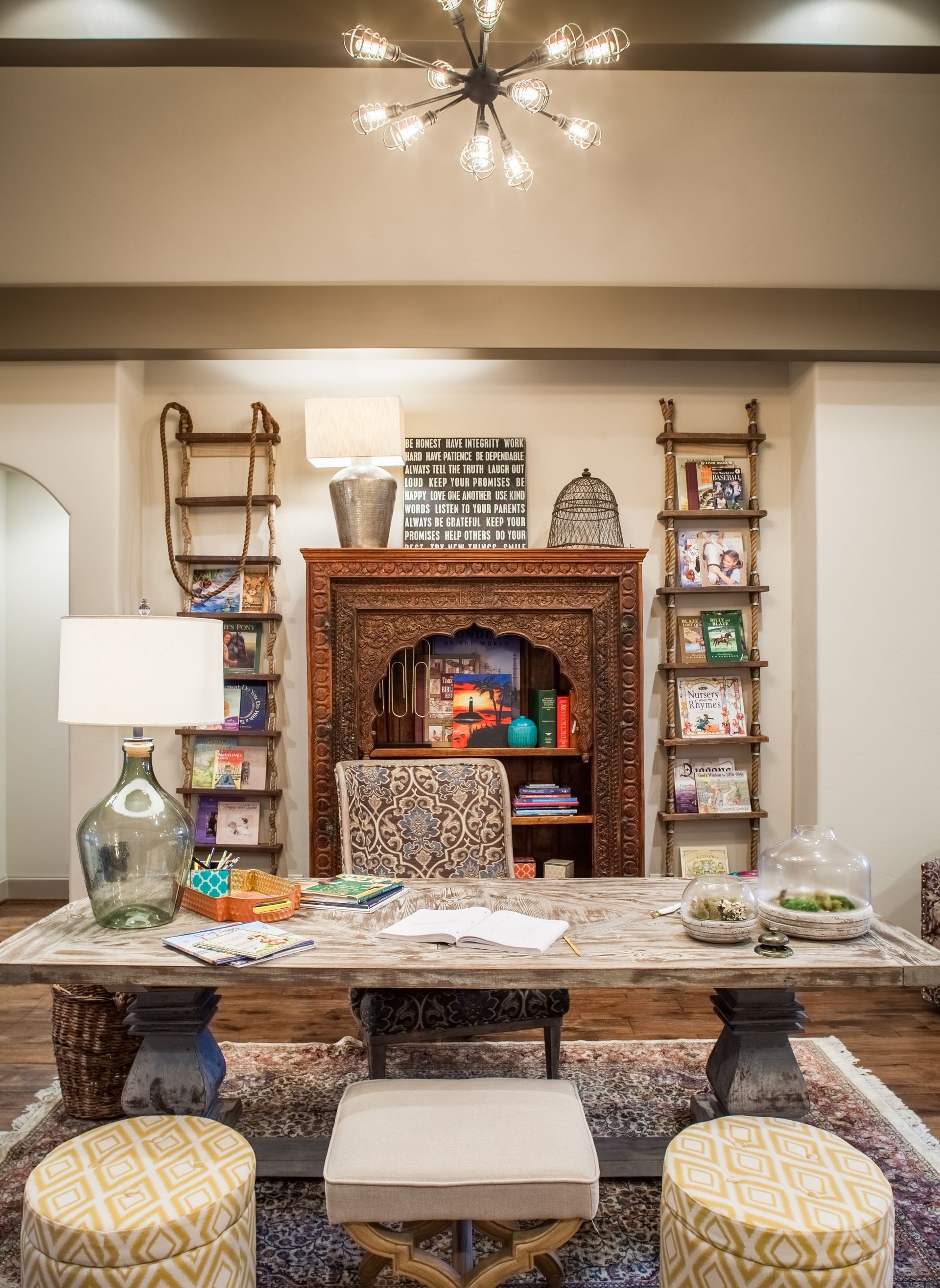 A living room with a table , chairs , ottomans and a fireplace.