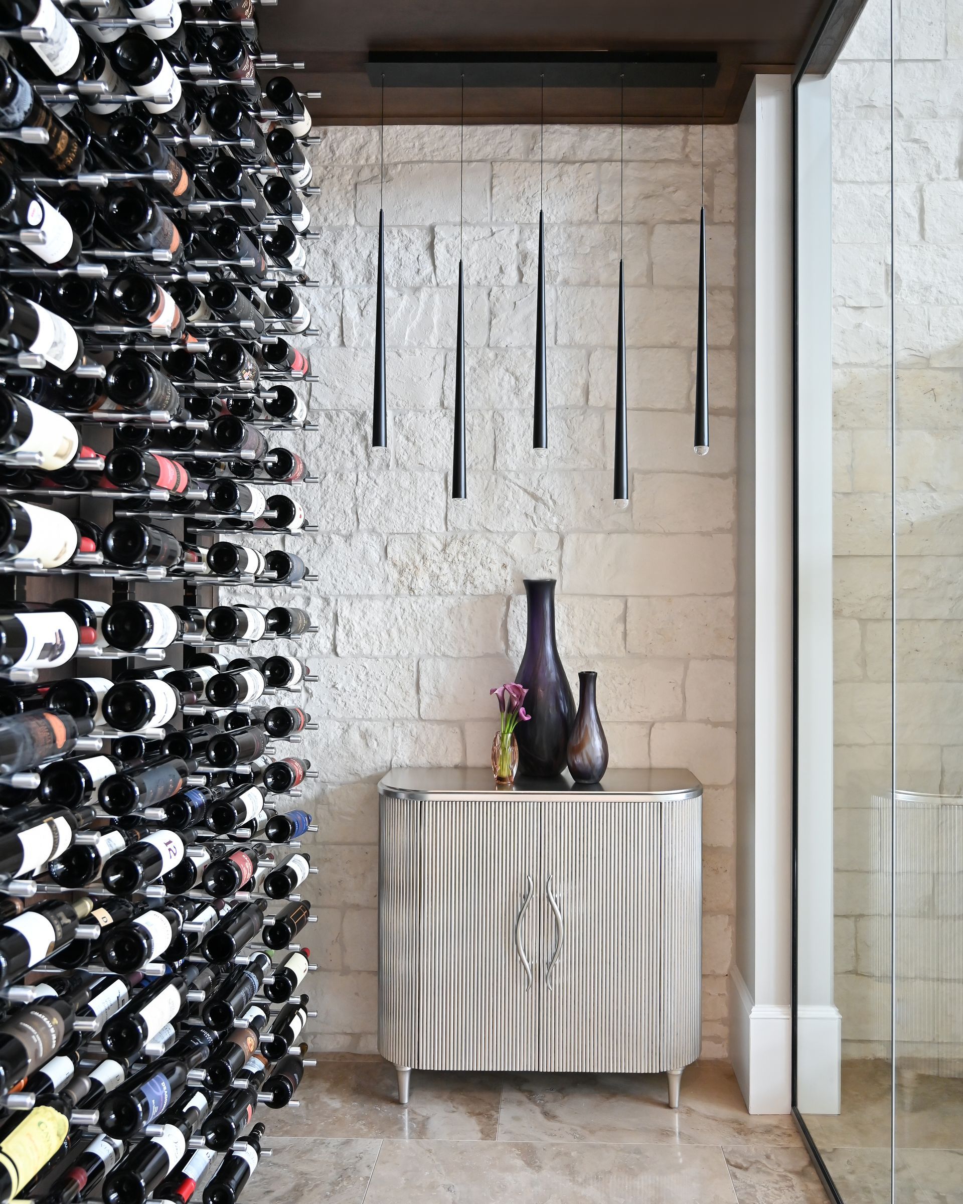 A room with lots of wine bottles and a stainless steel cabinet