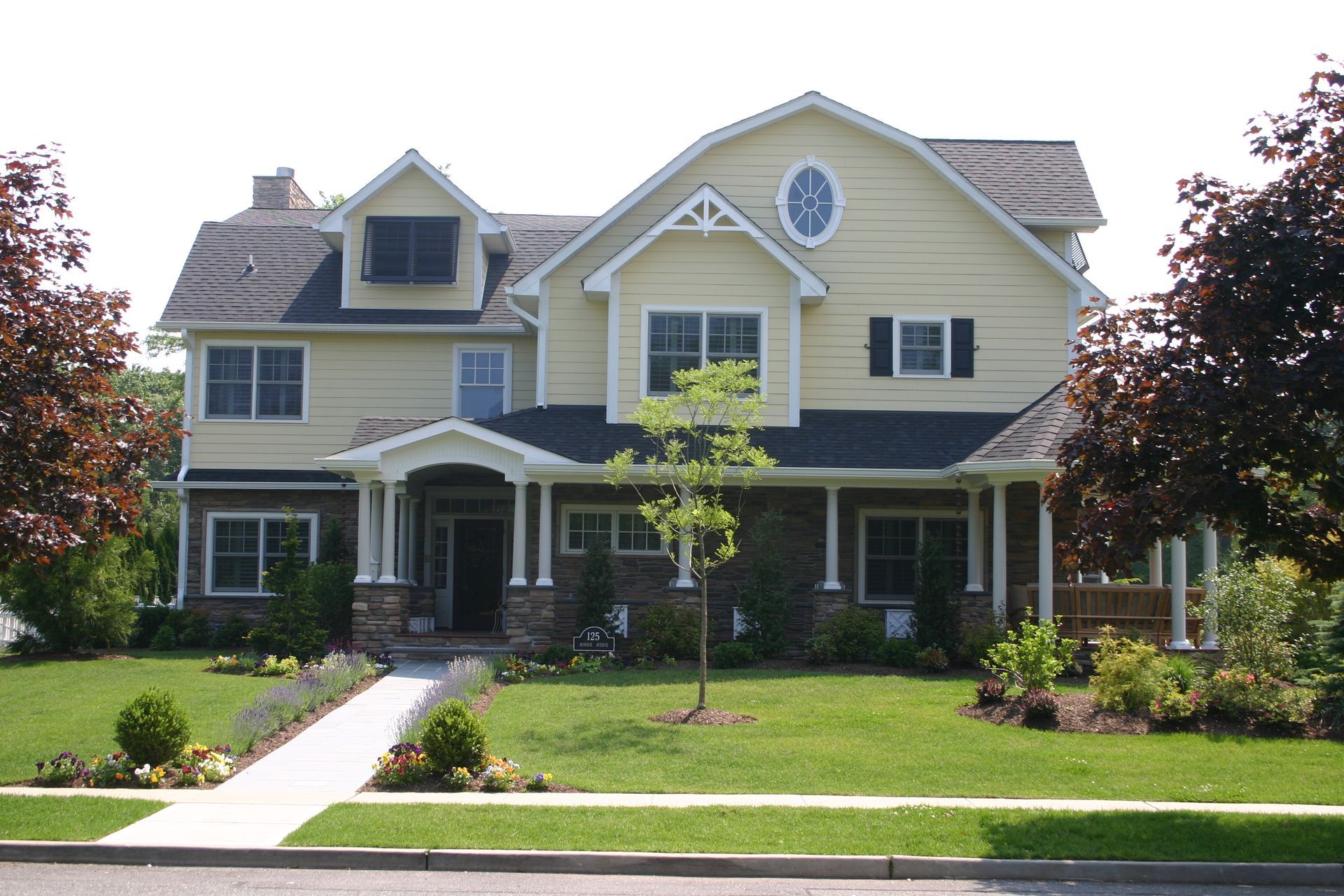 A modern house with a lot of windows and a large lawn in front of it.