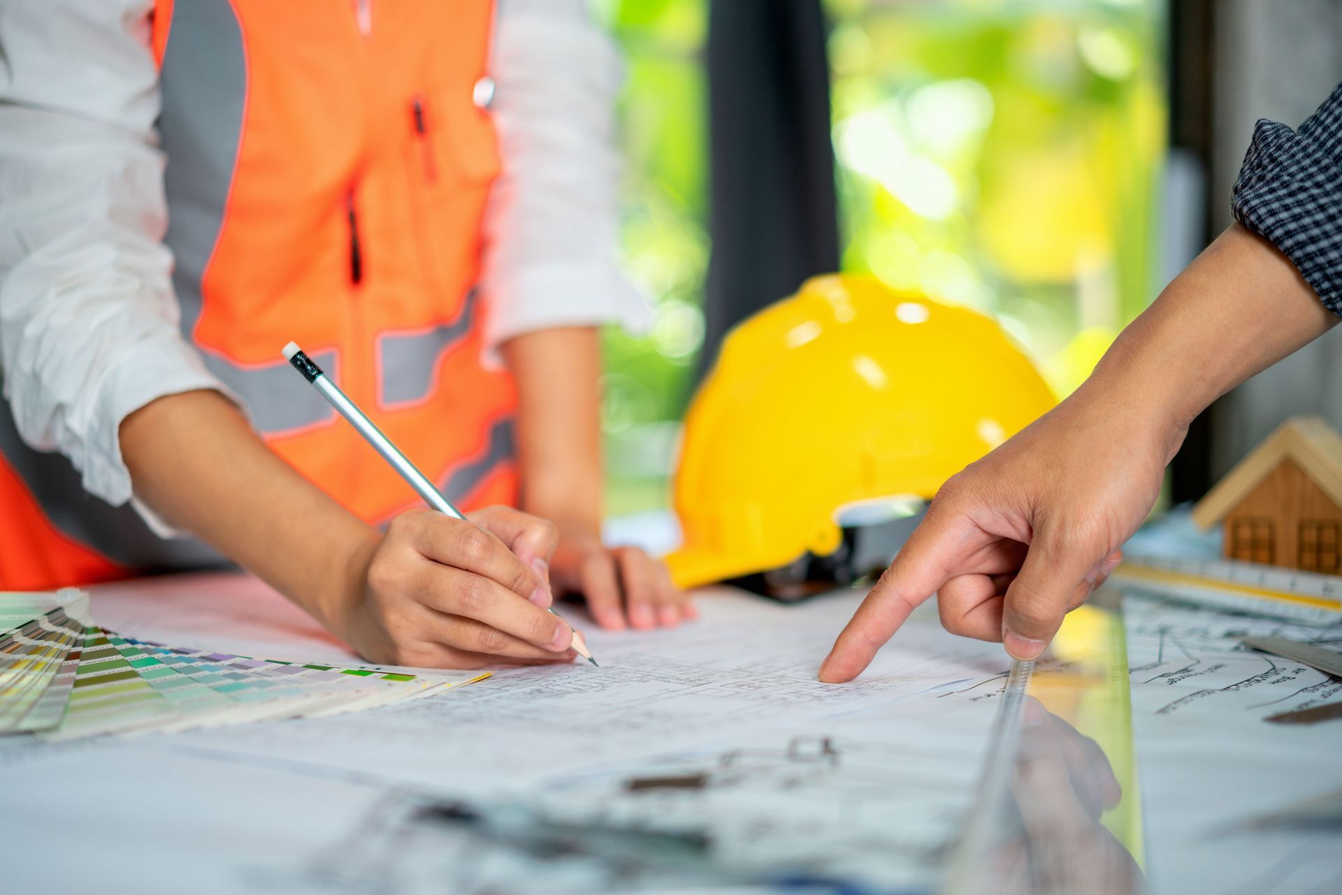 A couple of people are sitting at a table looking at a blueprint.