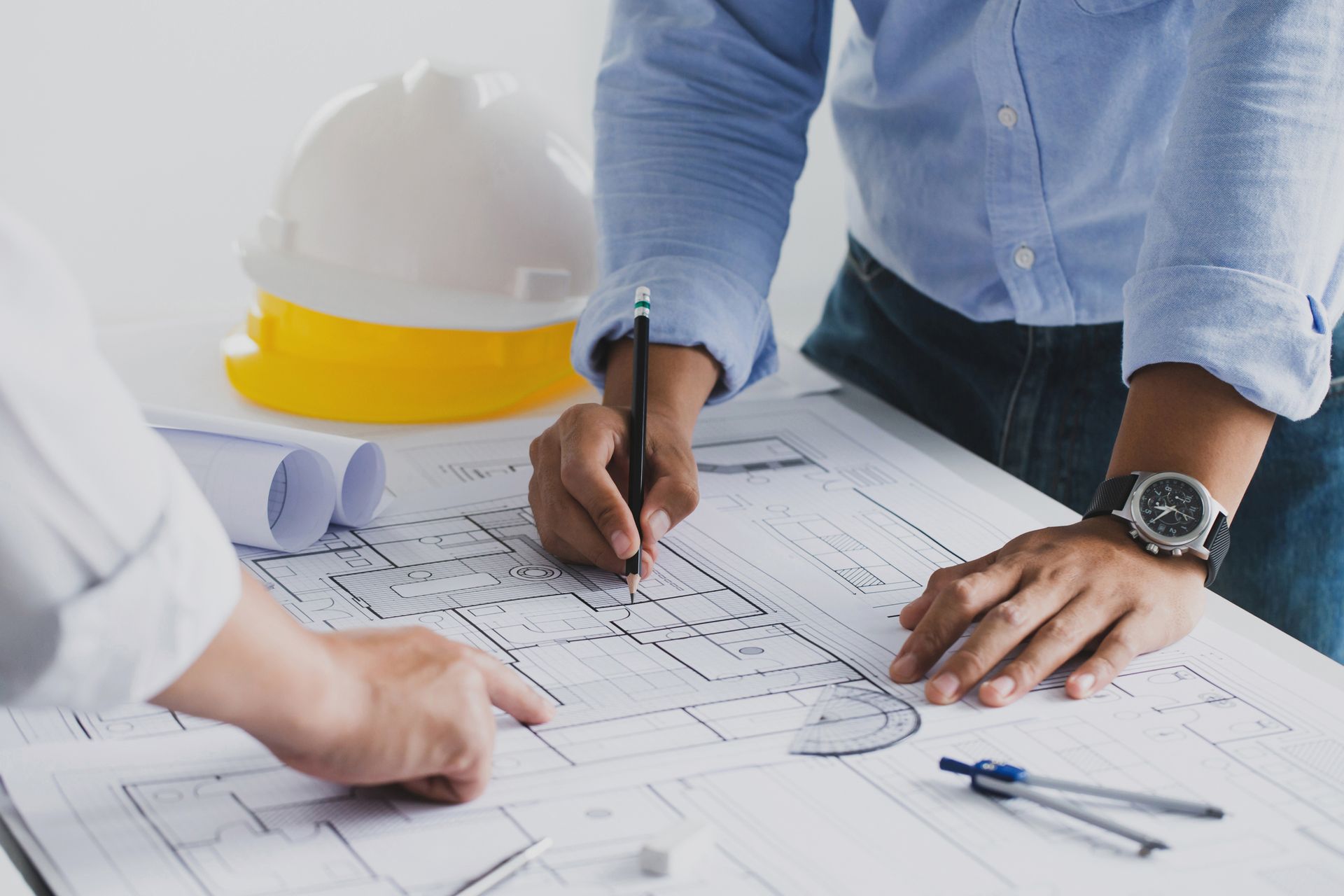 Two men are sitting at a table looking at a blueprint.