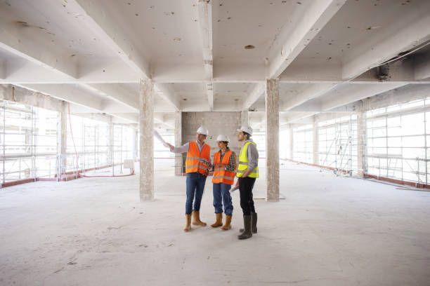 A group of construction workers are standing in an empty building under construction.