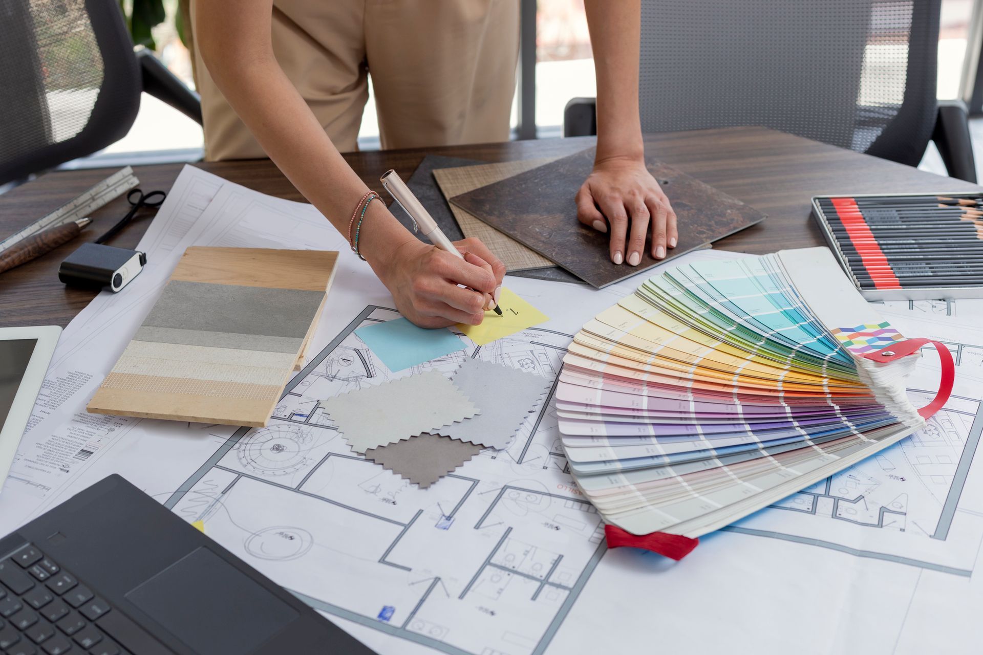 A woman is sitting at a table with a laptop and a pen.