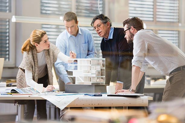 A group of people are looking at a model of a building.