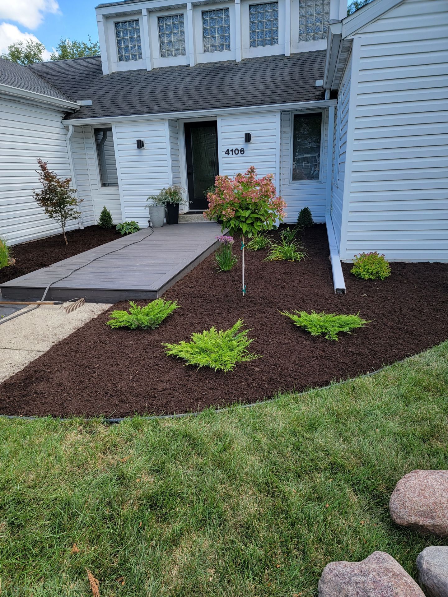 A white house with a lush green yard and new landscaping