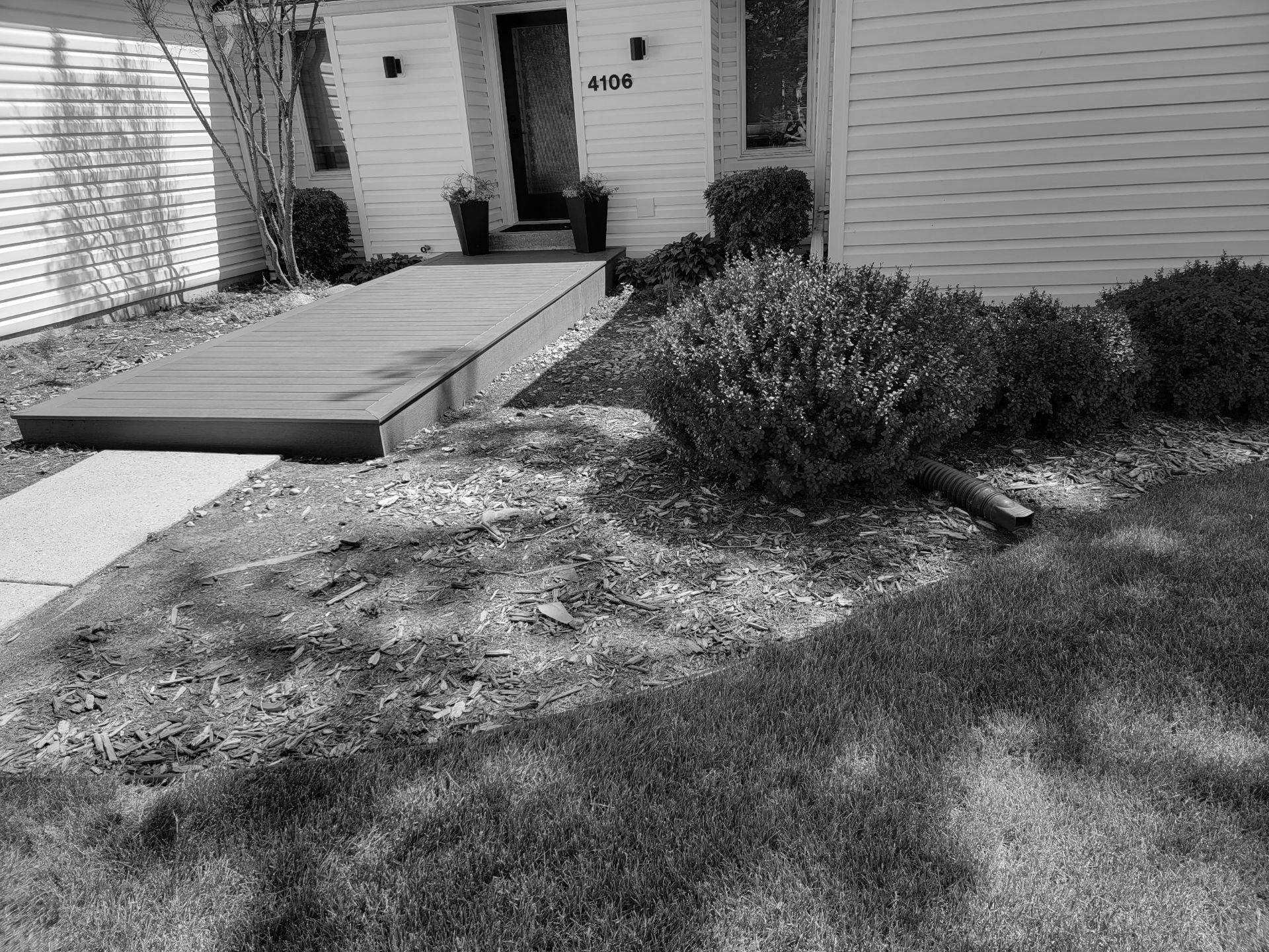 A black and white photo of a house with a ramp in front of it.