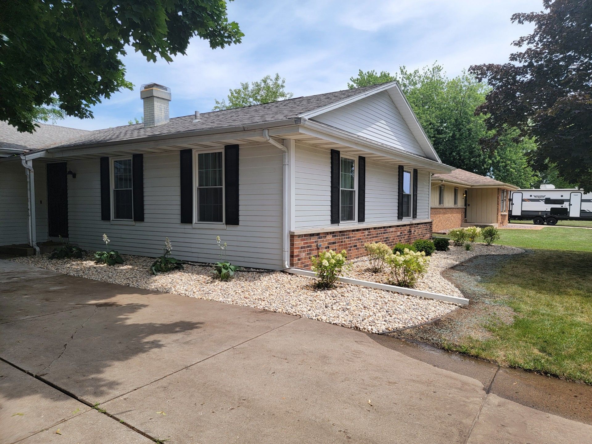 A white house with black shutters and a trailer parked in front of it