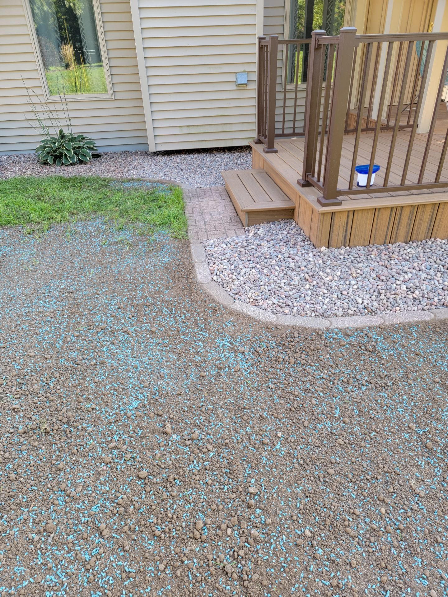 A driveway with a deck and stairs next to a house.
